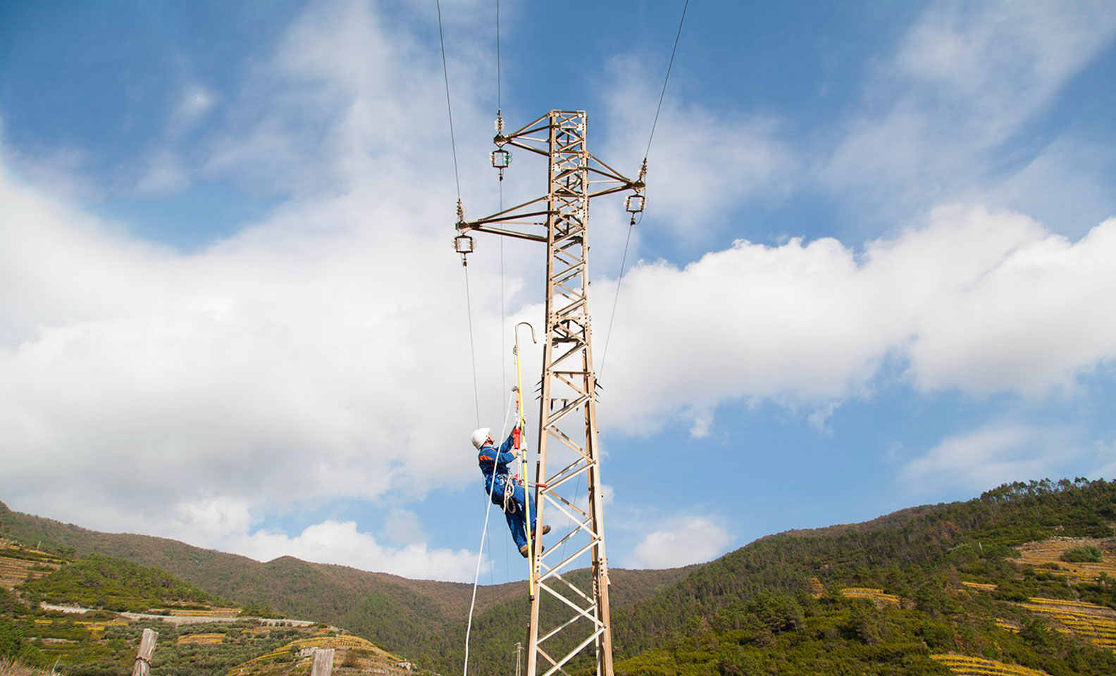 hombre sube al poste de luz con el cielo y las montañas de fondo