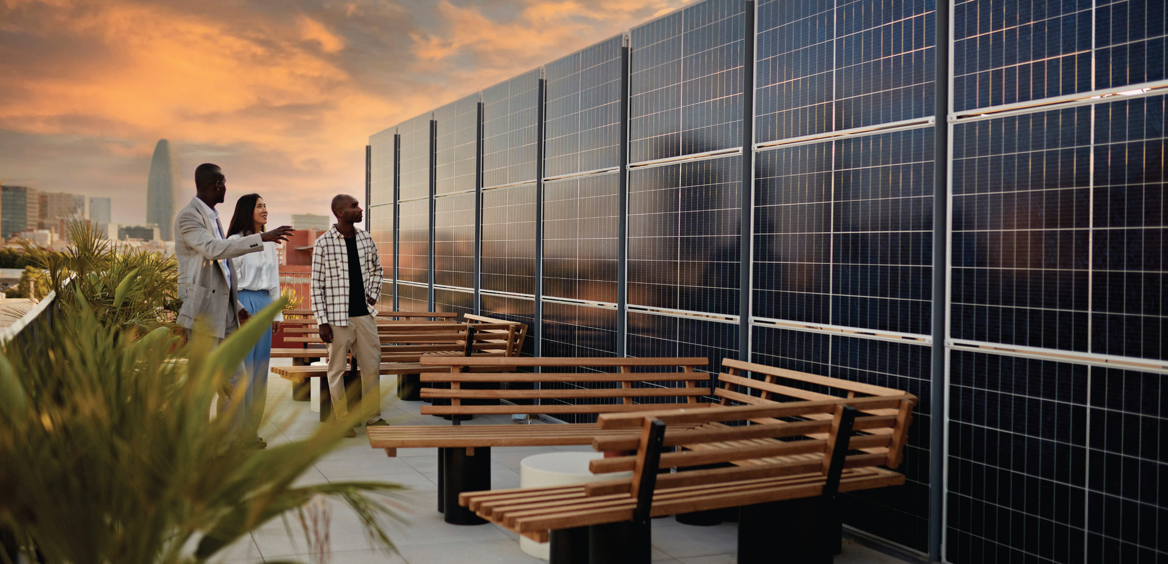 tre persone osservano un grande parete di pannelli fotovoltaici installata sul rooftop di un edificio in una grande città